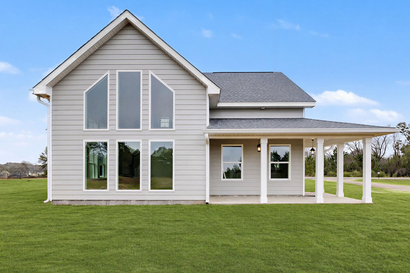 Daytime exterior of a gray farmhouse-style home with arched windows