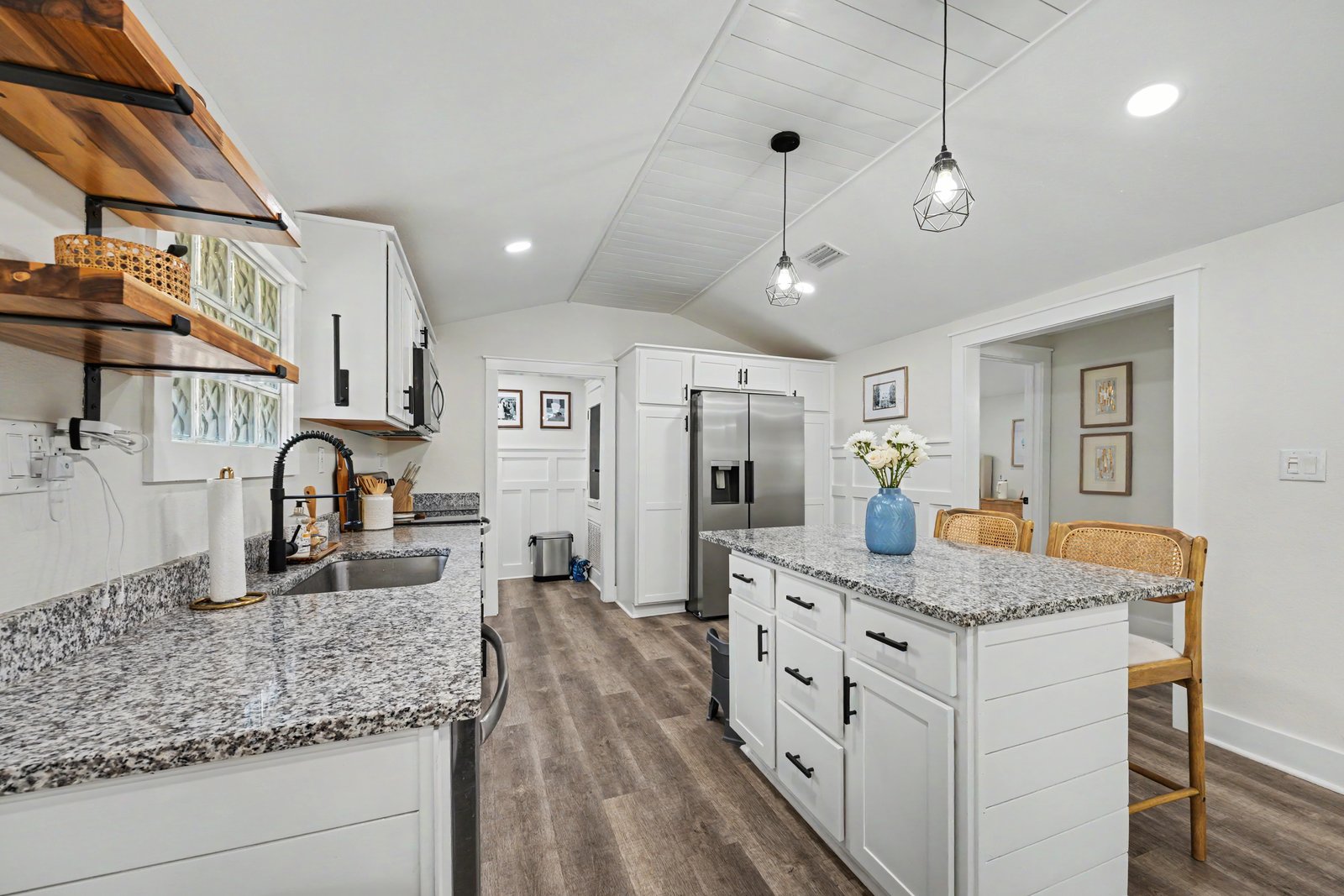 Bright white kitchen with shiplap ceiling and granite island