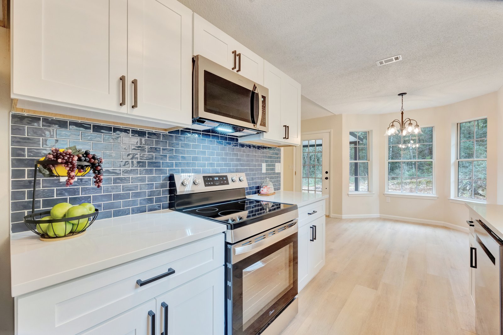 Bright kitchen with blue subway tile backsplash and light wood floors