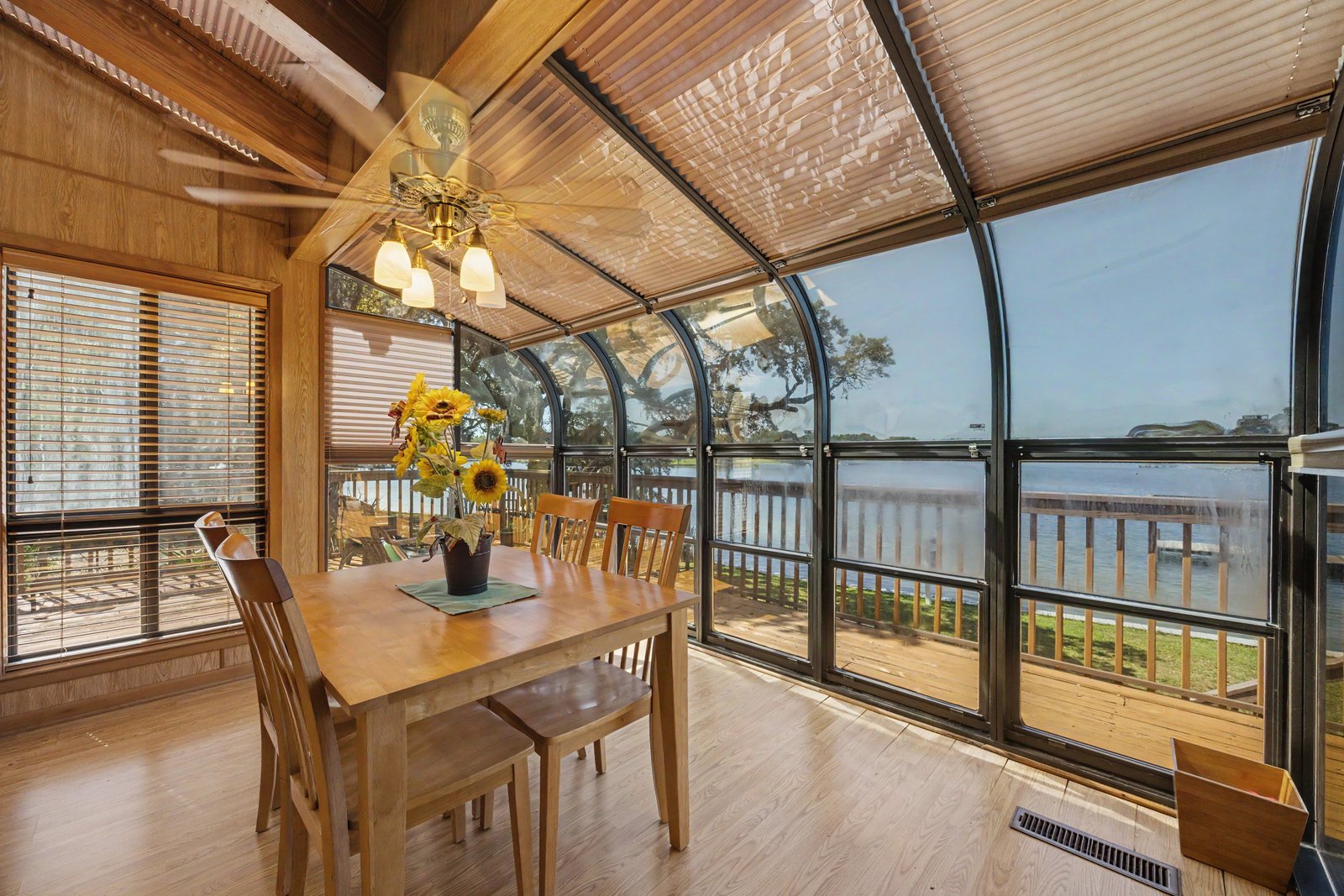 Lakefront sunroom with wood ceiling and arched windows over water